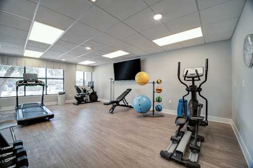 A spacious gym with a variety of equipment including treadmills, exercise balls, and weight machines.