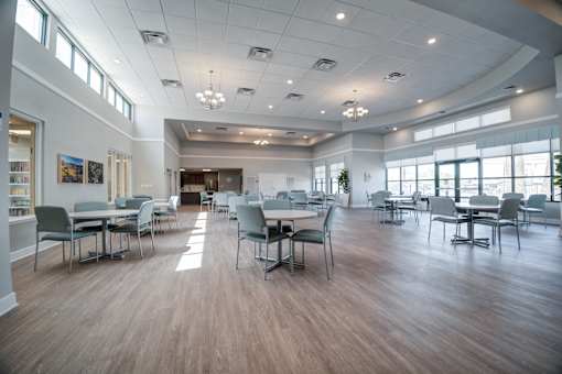 A large room with tables and chairs and a long table in the middle.