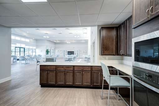 A kitchen with a white counter top and a white chair.
