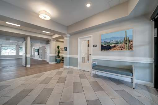 A hallway with a bench and a painting of a desert scene on the wall.