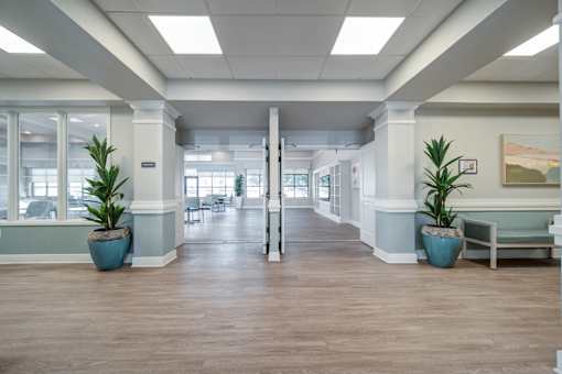 A long hallway with a bench and potted plants.