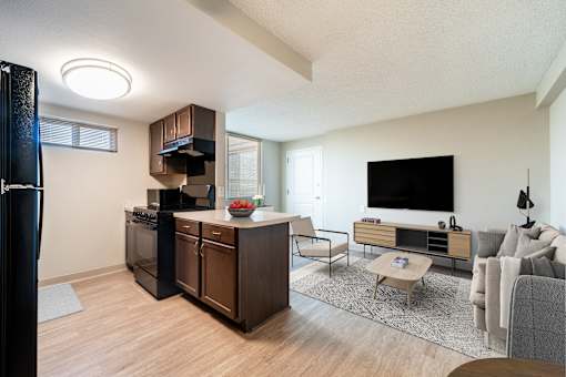 A modern kitchen with dark wood cabinets and a black refrigerator.