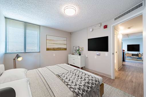 A bedroom with a bed, nightstand, and a painting on the wall.