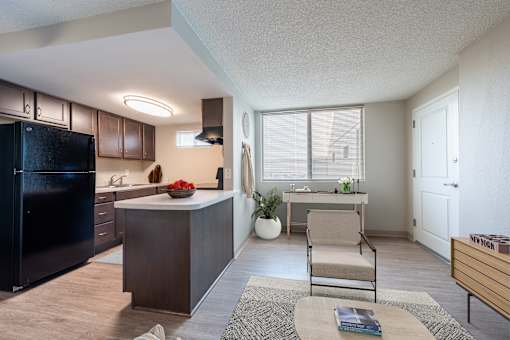 A kitchen with a black fridge, brown cabinets, and a wooden island with a bowl of fruit on it.