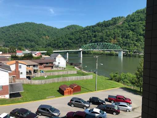 A parking lot with cars and a bridge over a river in the background.