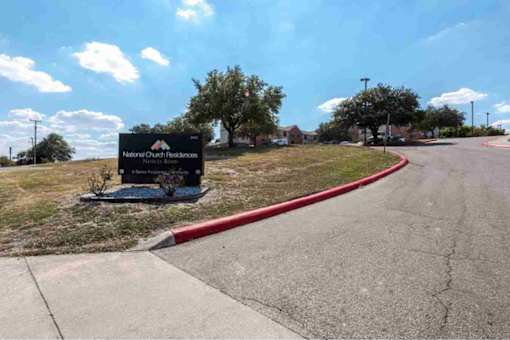 A sign for National Church Residences stands in the middle of a road.