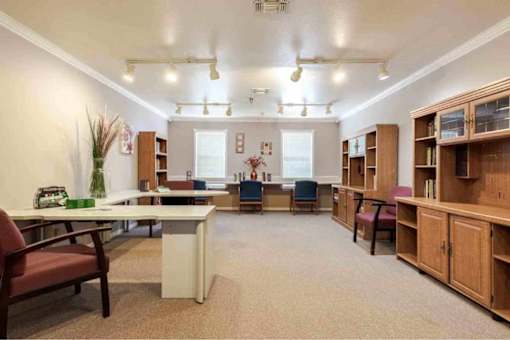 A room with a desk, chairs, and bookshelves.