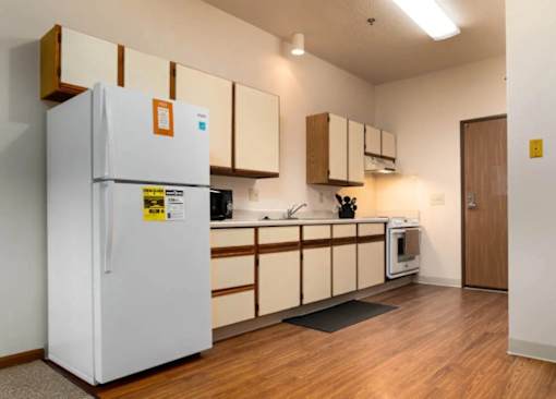 A kitchen with a white fridge and wooden cabinets.