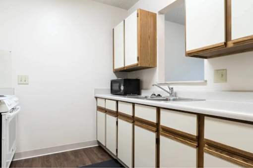 A kitchen with white countertops and wooden cabinets.