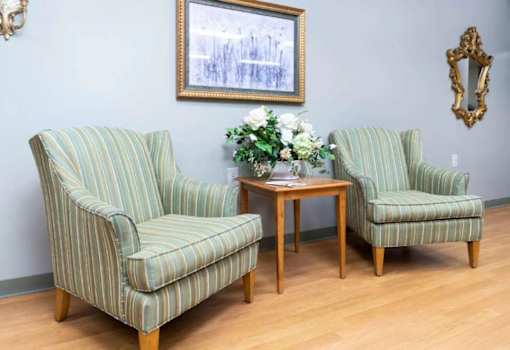 Two striped chairs and a small table with flowers on it.