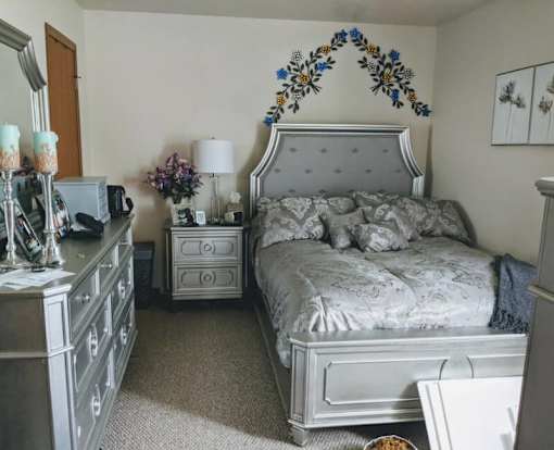 A bedroom with a large bed and a dresser with a mirror.
