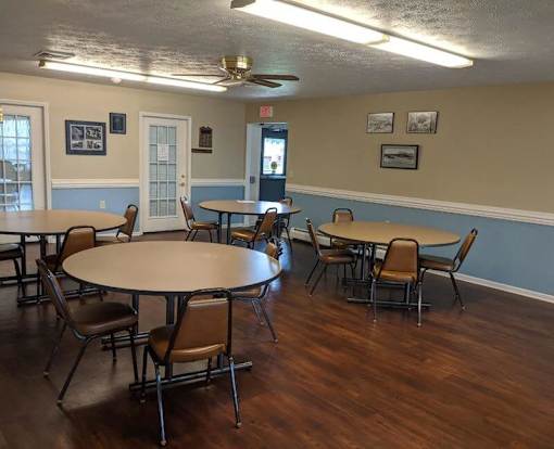 A room with tables and chairs and a ceiling fan.