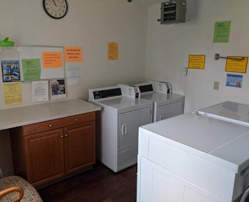 A laundromat with a clock on the wall and several washing machines.