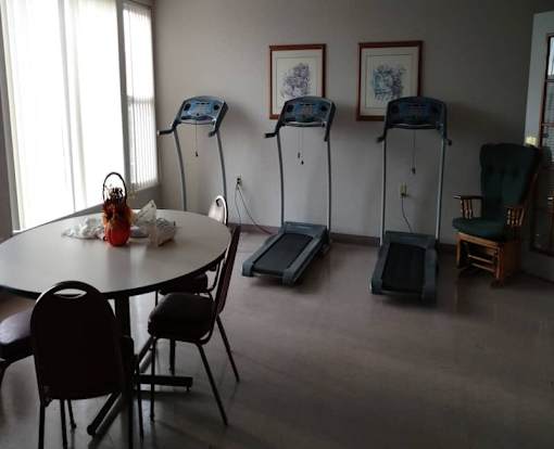 A room with a table, chairs and exercise equipment.