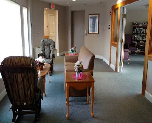 A room with a chair, a table, and a painting on the wall.
