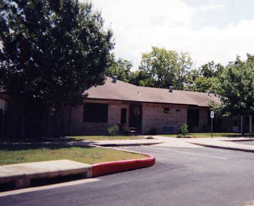 A building with a brown roof and a tree in front of it.
