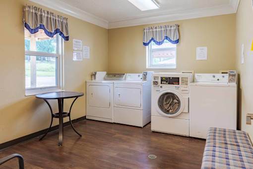 A laundry room with a washer and dryer, a table, and a bench.