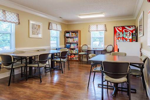 A dining room with a table surrounded by chairs.