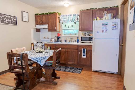 A kitchen with a table and chairs and a fridge.