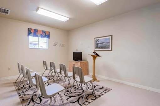 A room with a row of chairs and a television on a stand.