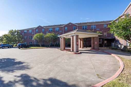 A parking lot in front of a red brick building.