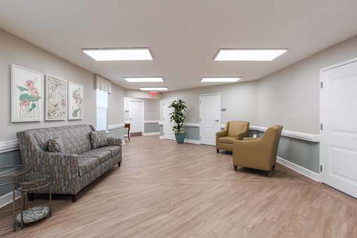 A waiting room with a couch, chairs, and a potted plant.
