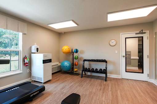 A room with a treadmill, a bench, and a clock on the wall.