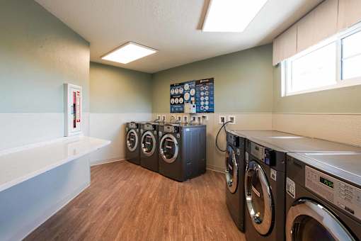 A laundry room with a row of washers and dryers.