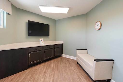 A living room with a flat screen TV mounted on the wall and a bench.
