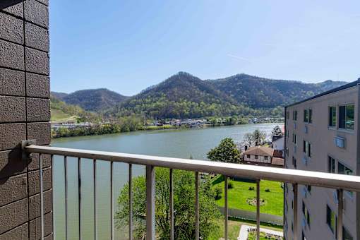 A balcony overlooks a river and a mountain.