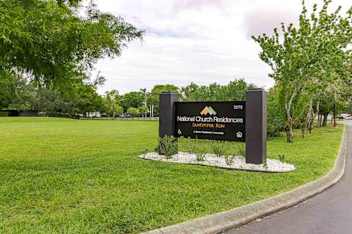 A sign for National Church Residences and Sandpiper Run stands in a grassy area.