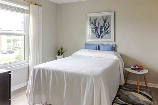 A bedroom with a white bed and a blue pillow.