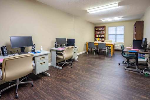 A room with multiple computer setups and chairs.