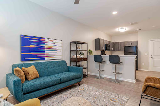 A living room with a blue couch and a painting on the wall at Sweetwater Point in Douglasville, GA
