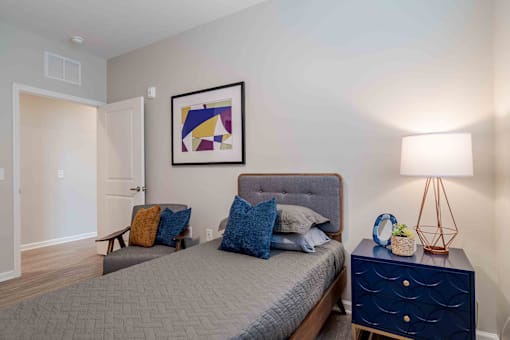 A bedroom with a bed, nightstand, and lamp at Sweetwater Point in Douglasville, GA