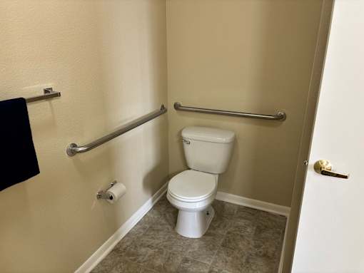 A white toilet with a towel rack and a towel hanging on the wall.