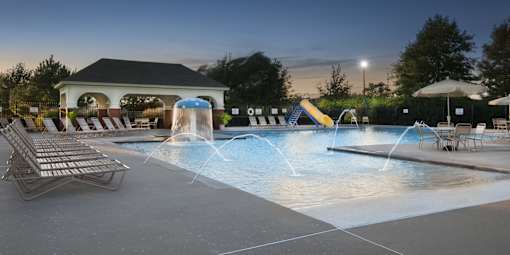 a nighttime view of a pool with a water slide and lounge chairs