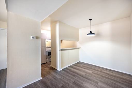 A room with a kitchen area and a hanging light fixture.