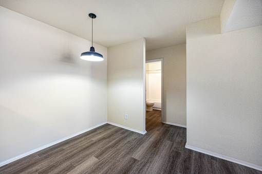 A room with a light hanging from the ceiling and a doorway leading to another room.