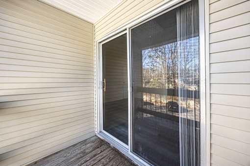 A sliding glass door on a house with a view of a tree and a car.