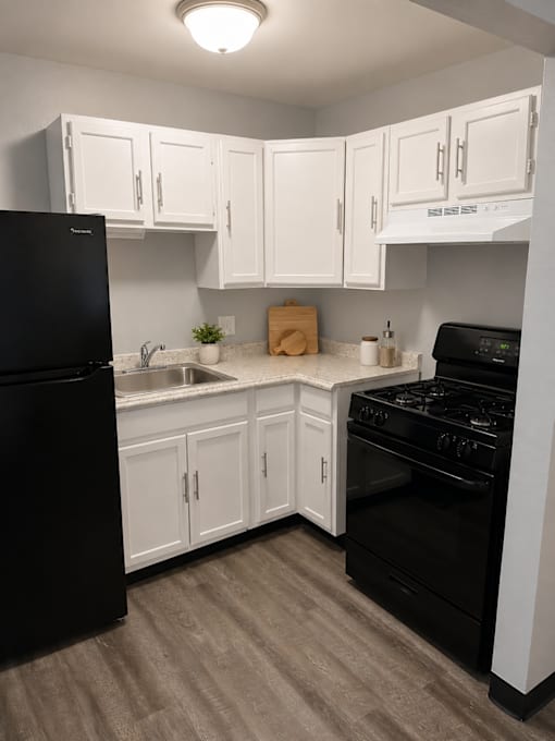 A kitchen with black appliances and white cabinets.
