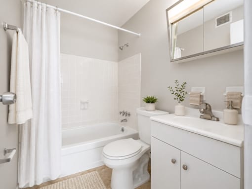 A white bathroom with a toilet, sink, and bathtub.