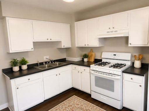 A white kitchen with black countertops and a white stove.