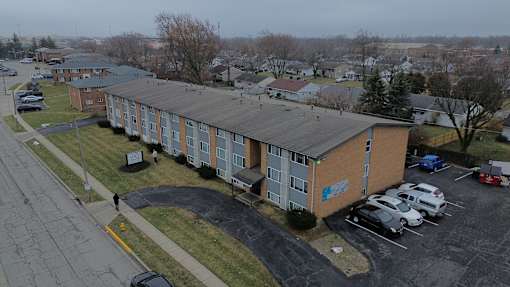 A parking lot in front of a building with cars parked.