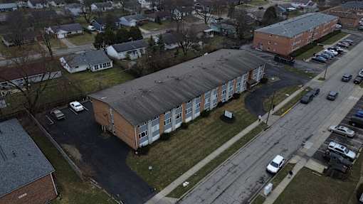 A parking lot is in front of a building with a long row of cars parked.