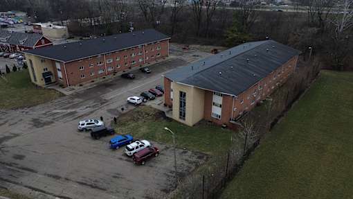 A parking lot with cars and two buildings in the background.