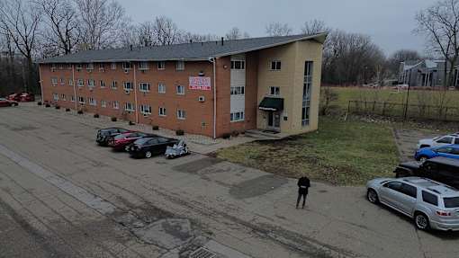 A parking lot with cars and a person standing in front of a building.