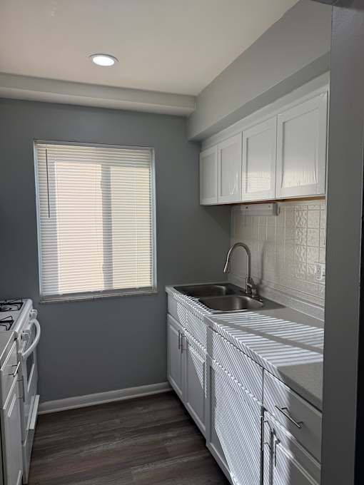 A room with a window covered by blinds and a white ceiling with a vent.
