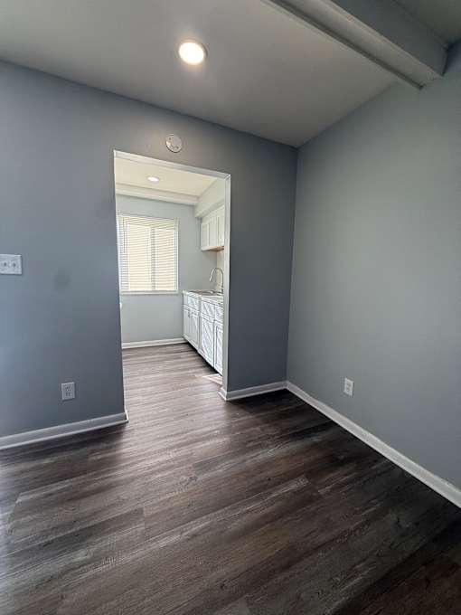 A room with a grey wall and a wooden floor.