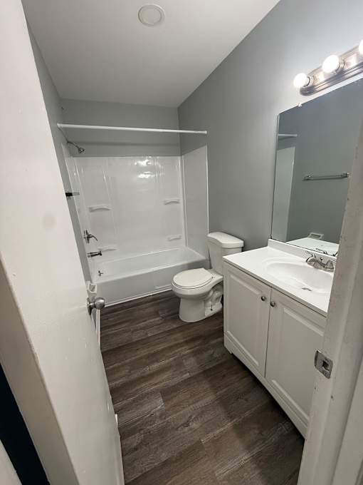 A bathroom with a toilet, sink, and mirror.